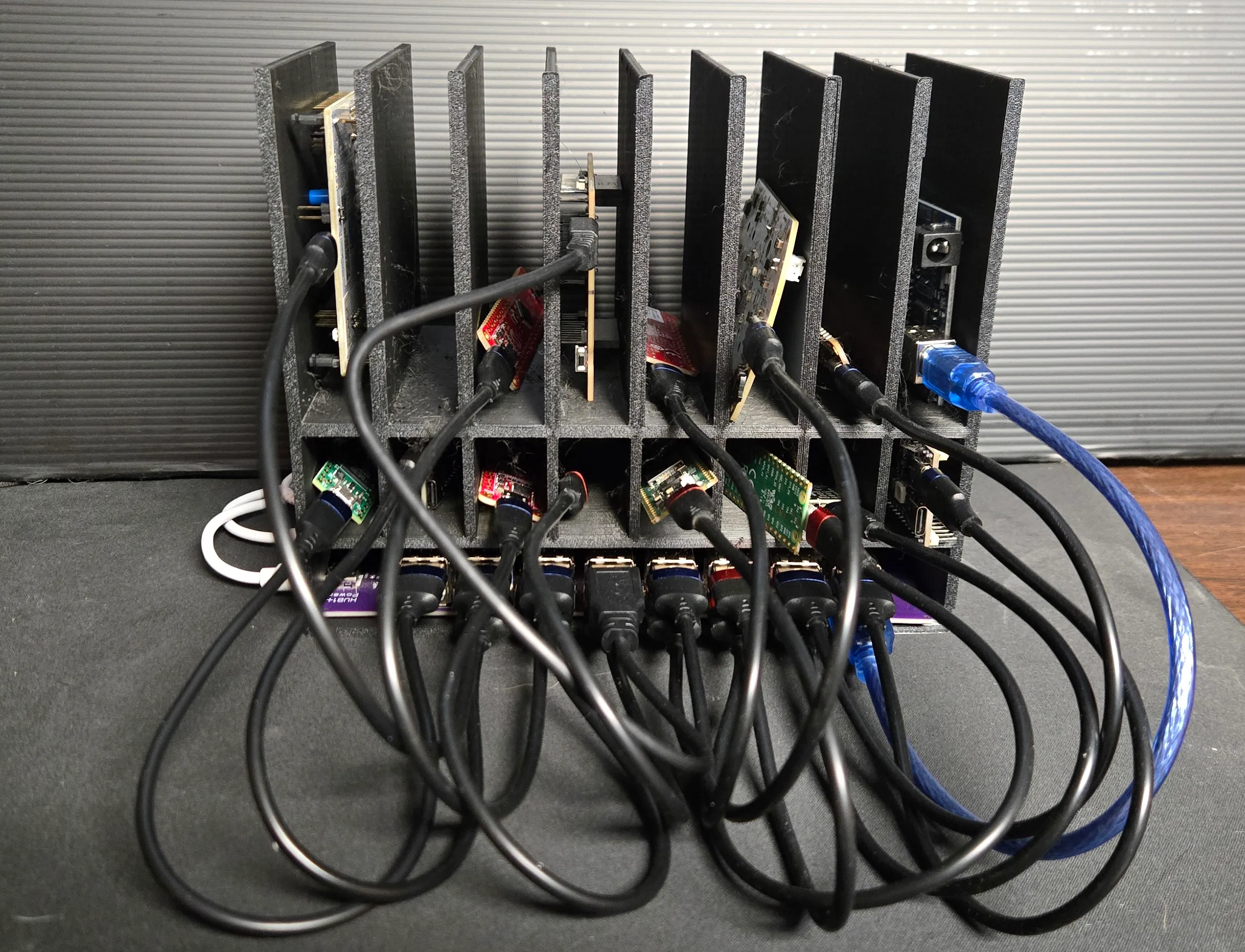 The finished enclosure loaded: dev boards standing upright in the divider bays, their cables dropping down to the USB row on the carrier PCB in the base